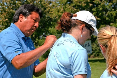 Legendary U of W quarterback Sonny Sixkiller adds his signature to a growing list collected by Islanders Bank's Brenna Woods at the 2010 Celebrity Golf Classic.