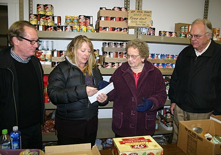 Nancy Young presents donations to Food Bank President Dorothy Lawson as Michael Linehan and Denny Holm look on