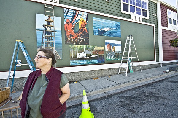 San Juan Island artist Annie Howell-Adams hangs her mural on the Nichols Street side of the Ace Hardware building