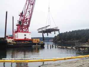 A barge and crane help in the removal of creosote pilings and a pier from Lopez Island’s Barlow Bay.
