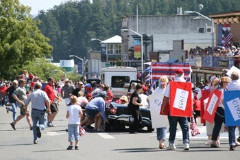 Onlookers rush to into the street and lift up a convertible to rescue a young girl trapped beneath it the wake of a collision at the annual Friday Harbor Fourth of July parade.