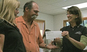 OPALCO’s Anne Bertino presents Frank and Christine Beckert with a check