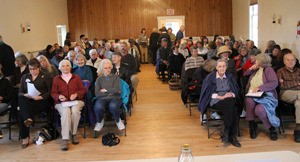 A standing-room-only crowd packs the Grange for a League of Women Voters forum on health care
