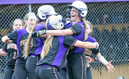 The Wolverines converge at home plate to celebrate teammate Lauren Ayers and her fifth-inning solo home run in the Wolverines league title clinching victory at home over Darrington