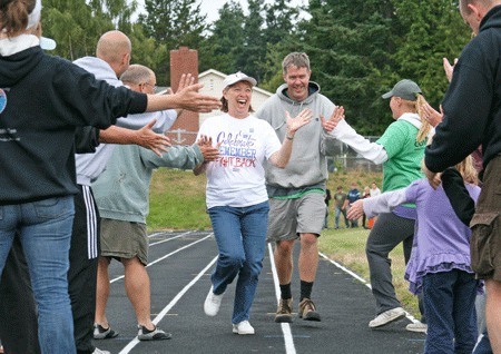 Judy Cornell and Patrick Minney are greeted with cheers and high-fives on the final lap of Relay For Life 2011.