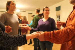 Dancers hold hands in a contra dance at the Grange. The solstice celebration will include dancing