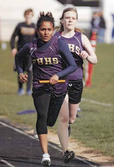 Friday Harbor senior Dasuni Gurushinge takes the baton from teammate Mandy Turnbull in the final leg of the 2 x 400 relay at the four-team track and field meet March 30 in Friday Harbor. The Wolverines finished second