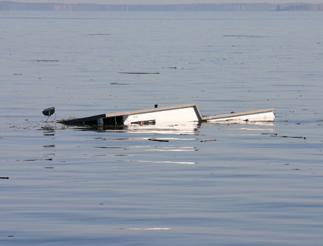 A partially submerged houseboat — its satellite dish clearly visible at left — floats off Eagle Point