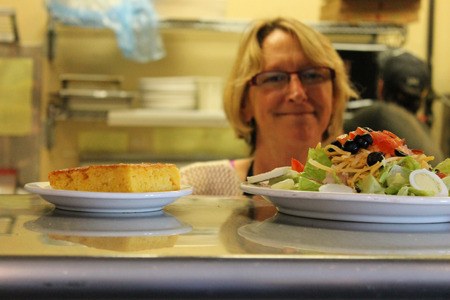 The Good Karma Cafe’s Merrie Roop places a salad and slice of corn bread in the window