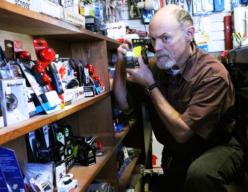Paul Ahart tests one of the headlights he sells at Island Bicycles.