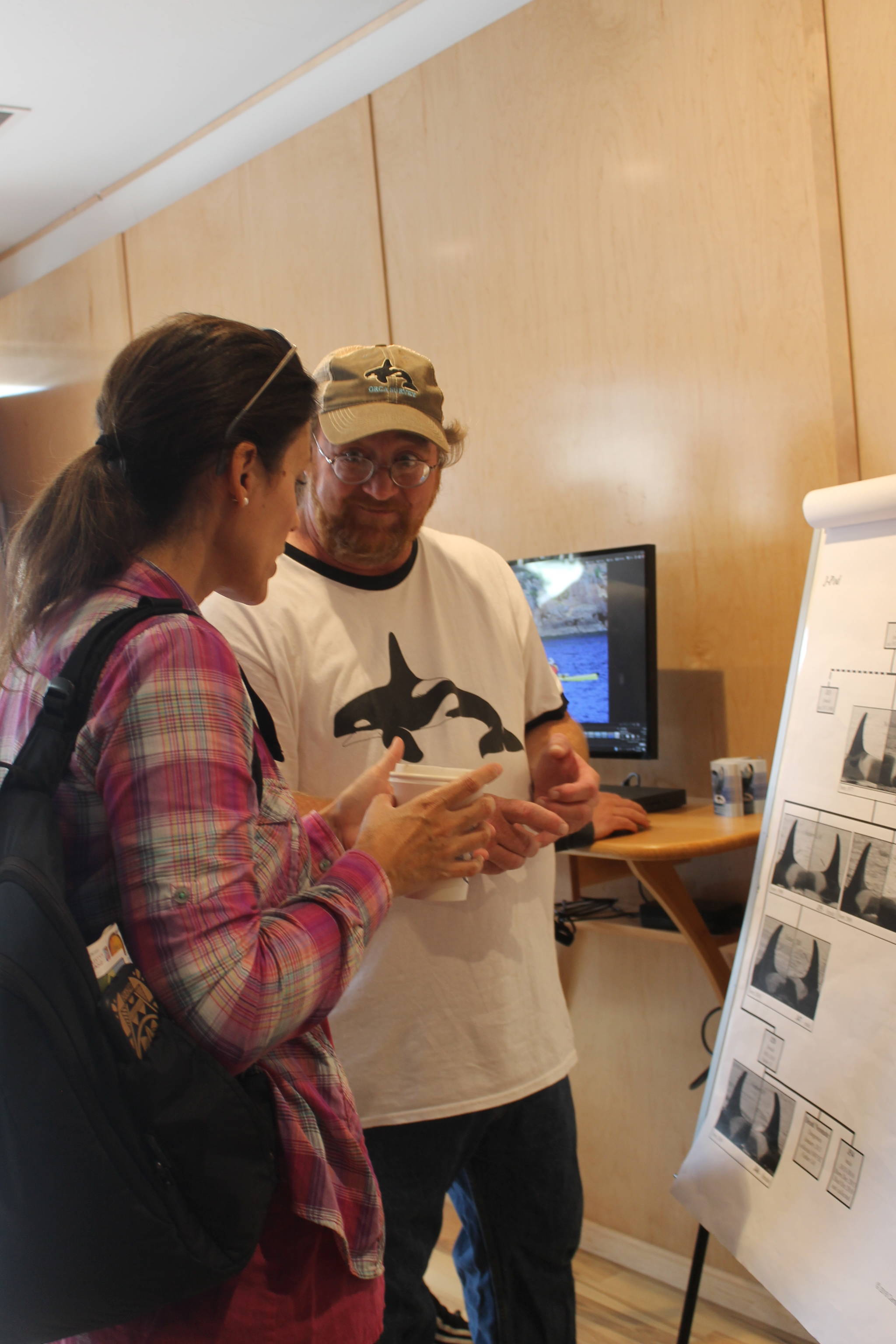 Staff photo/Heather Spaulding. Dave Ellifrit, photo ID specialist talks with a visitor about Orca IDing.