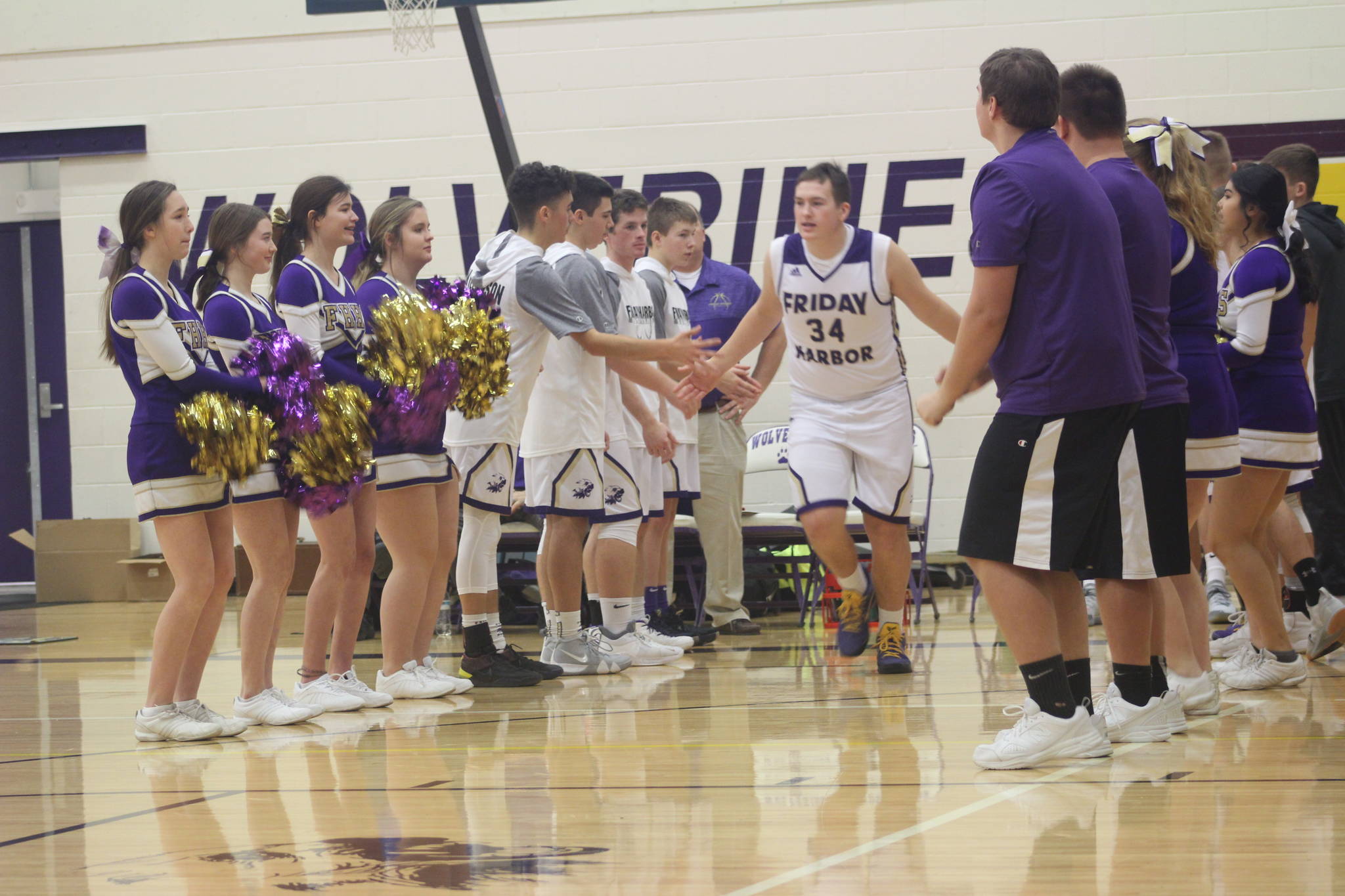 Staff photo/ Heather Spaulding. Cheerleaders welcome the boys team starting line up to the court.