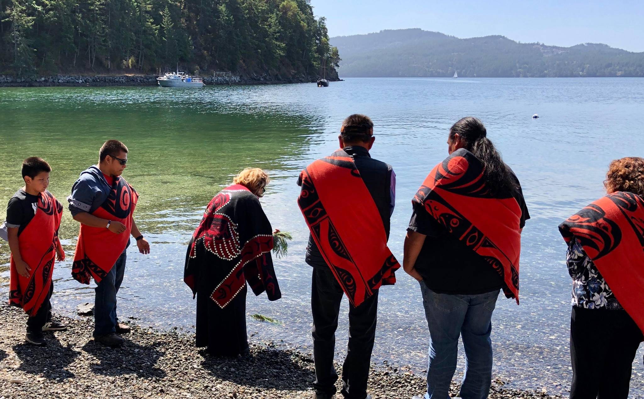 Lummi ceremonialist Tyson Scarborough with Lummi elder Raynell Morris placing cedar boughs in water as part of naming ceremony. Also pictured: witnesses Kevin Paul (Swinomish Tribe); Rueben George (Tsleil-Waututh Nation); Chief Leah George-Wilson (Tsleil-Waututh Nation). <em>(Photo: Lummi Nation Business Council)</em>