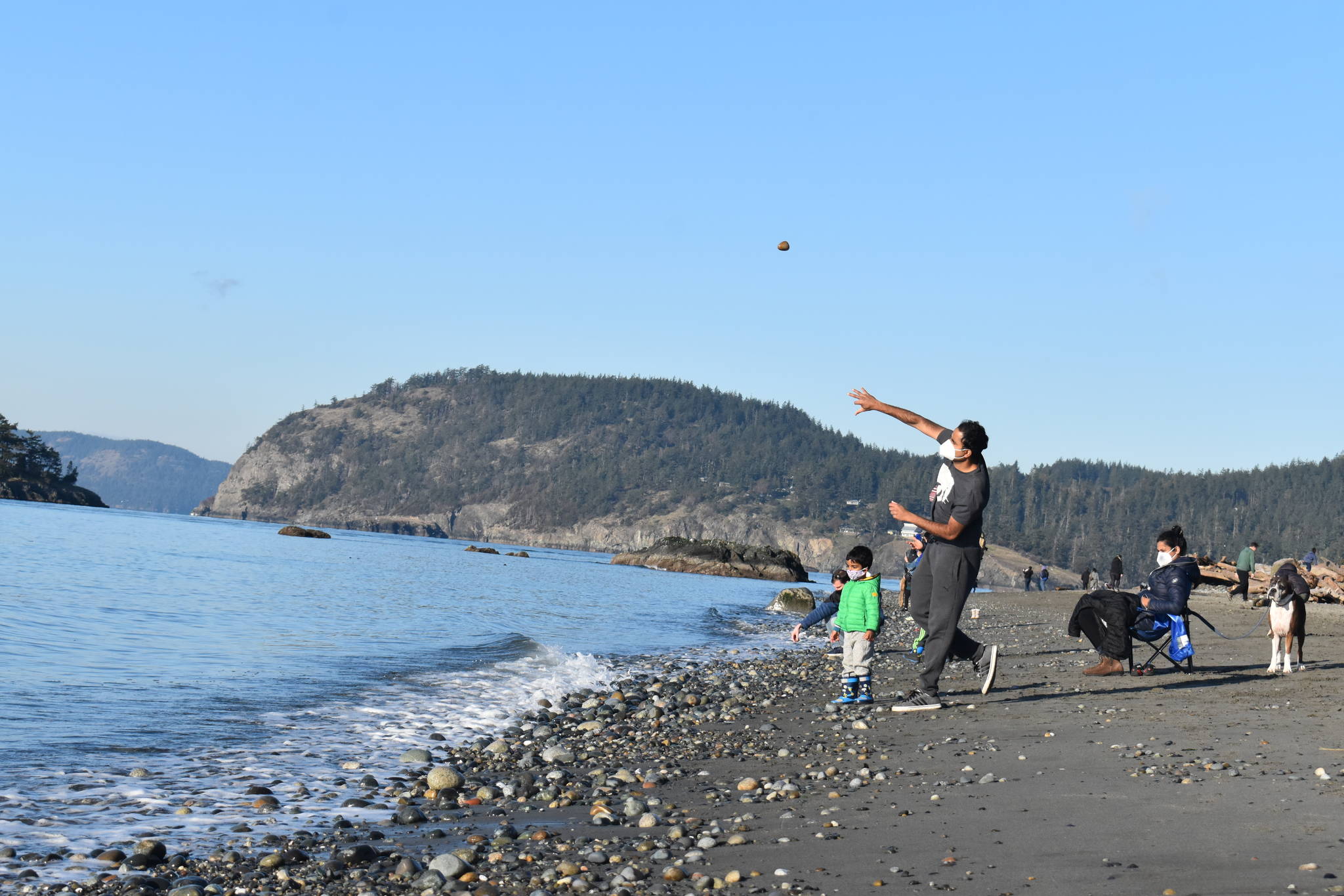 Raghu Maddirala of Bellevue and son Arjun, 3, throw rocks at West Beach in Deception Pass State Park last Saturday. The park would be used as a Navy training site along with others on Whidbey under a new five-year proposal. Photo by Emily Gilbert/Whidbey News-Times