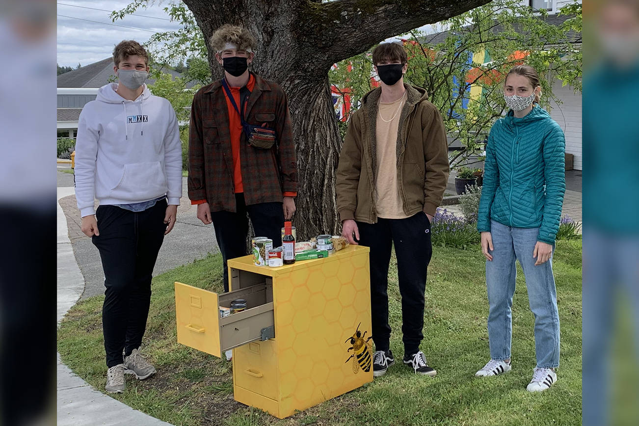 A stocked food distribution cabinet outside of Spring Street International School. From left to right, Spring Street students Julian Rich, Francis Black, Zach Stults, and Linnea Morris. (Contributed photo)