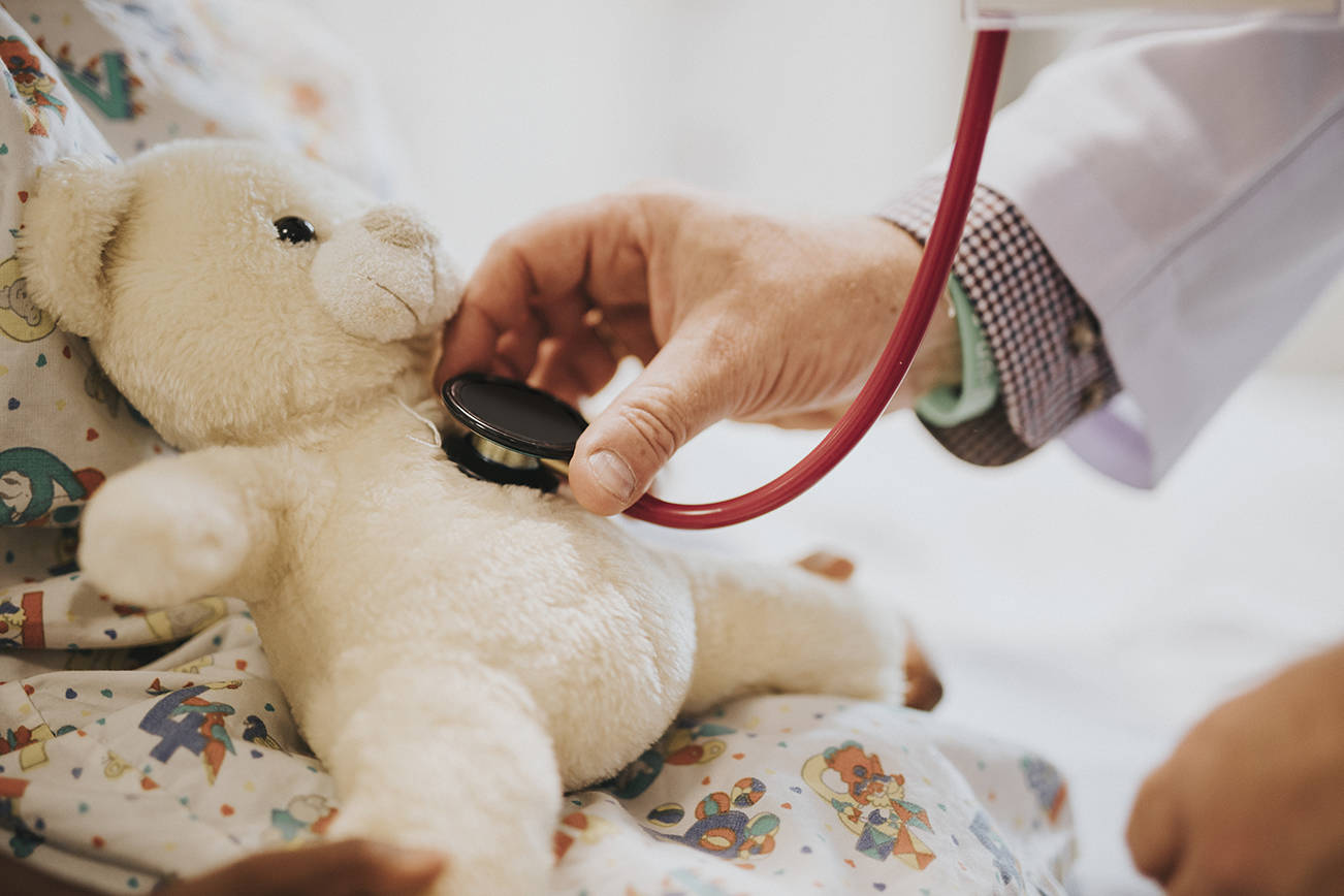 Doctor playfully checking the heart beat of a teddy bear - Free adobe creative stock
