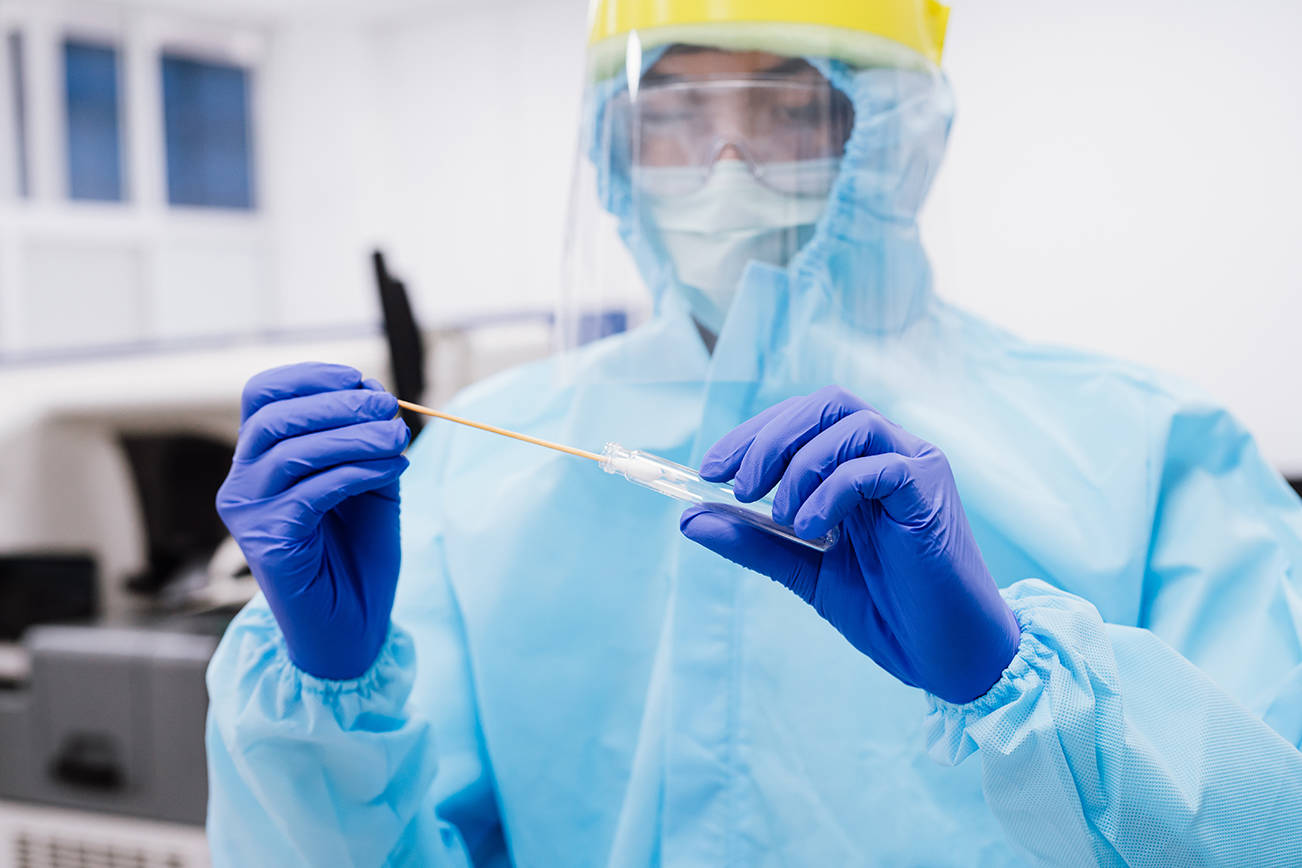 Medical scientist in PPE suit uniform holding  swab coronavirus test in laboratory. Adobe stock