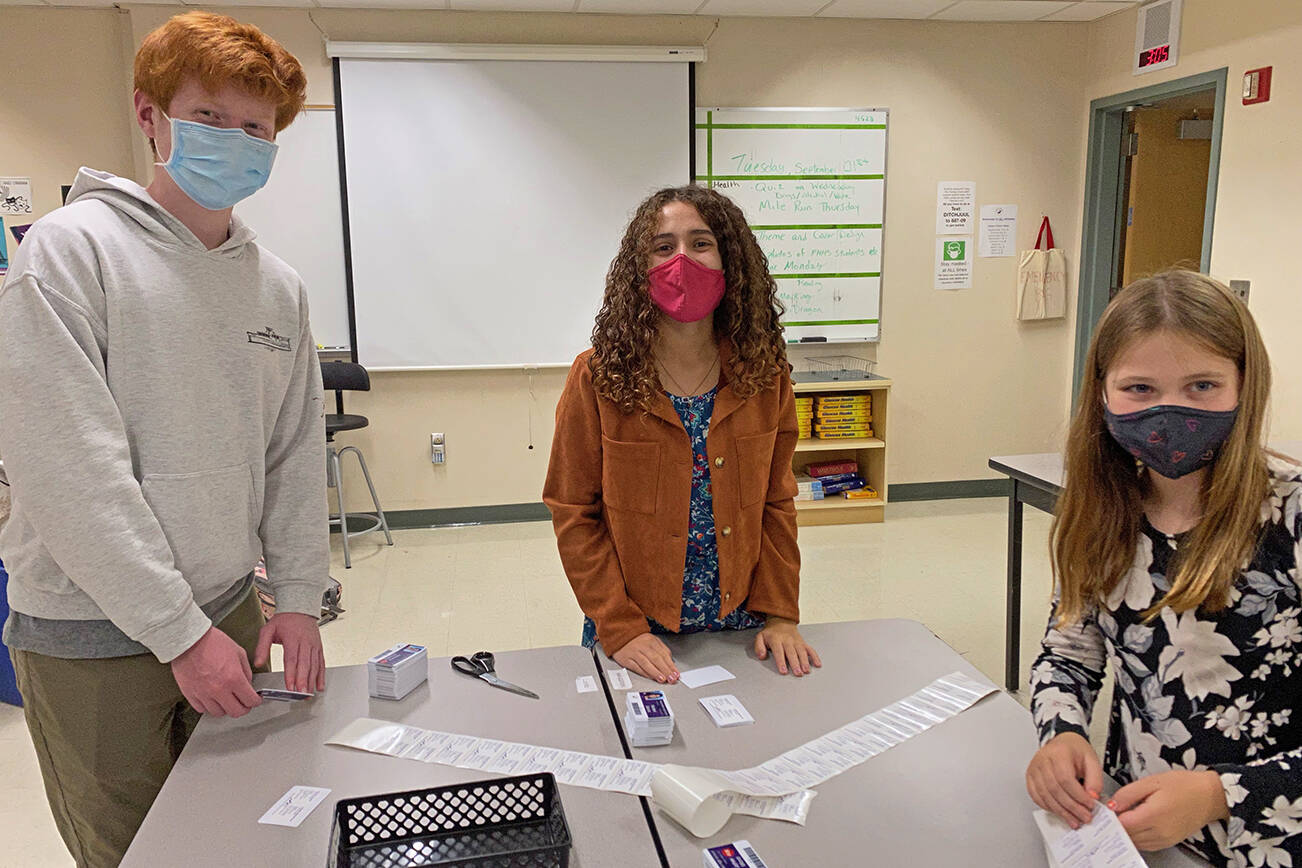 Contributed photo
Luke Fincher and Madison and Maile Buehler put prevention resource stickers on Friday Harbor schools’ student ID cards.