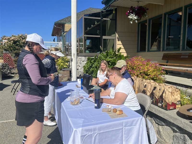 Contributed photo
Players Sue Blaker and Libbey Nixon check out the Wine Raffle and Golf team member Morgan Douglass oversees the donations.