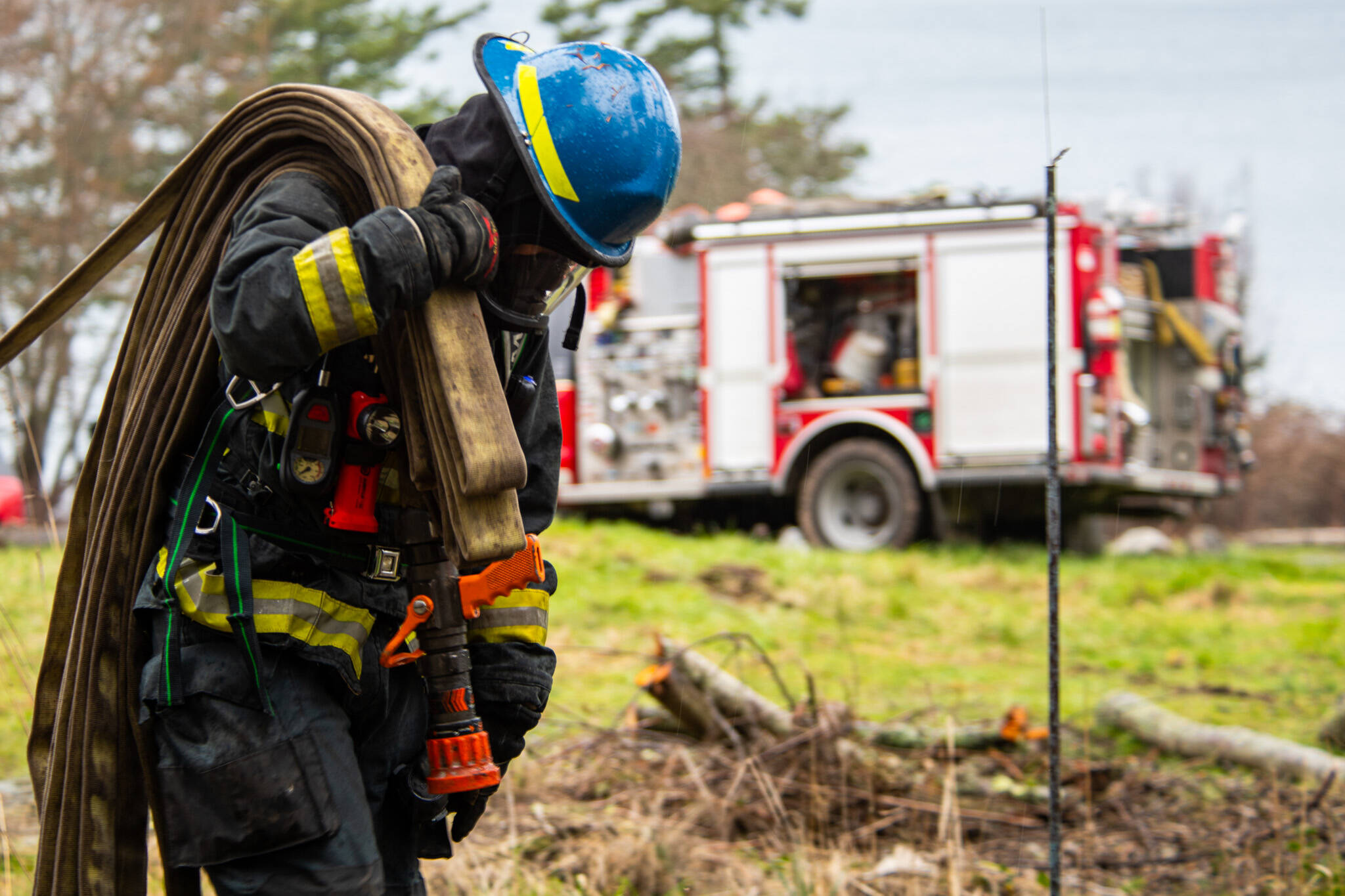 A firefighter recruit pulling deploying hose at live fire training in February.