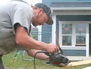 Anders Rehban shaves a shingle down to size for a neighboring 'sweat equity' home in Homes for Islanders Village Grove neighborhood.