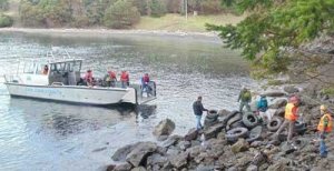 A cleanup crew relies on a sheriff's boat to remove a mass of tires dumped on the waterfront of the Land Bank's Deadman Bay preserve in mid-March