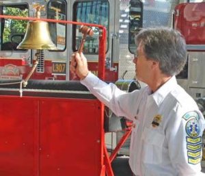 Francis Smith of San Juan EMS rings a ceremonial bell at the conclusion of a 'Remembrance Ceremony'