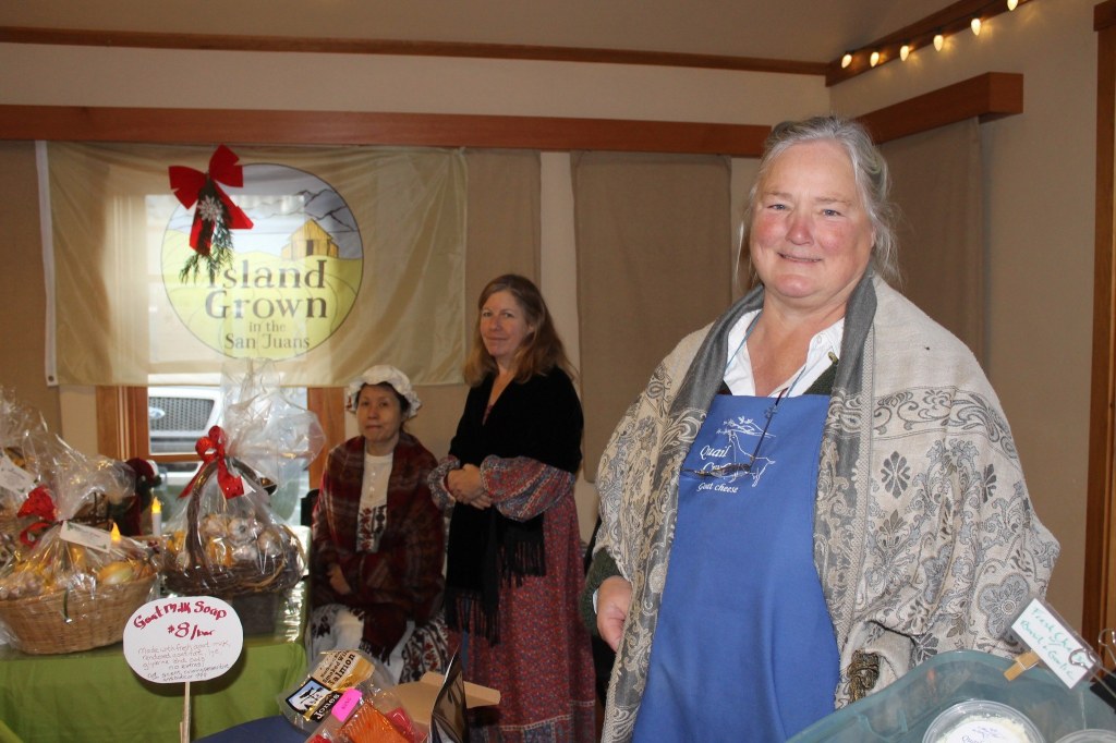 Staff photo/Hayley Day                                Layne Sundberg of Quail Croft goat cheese and Sandy May and Carol Liu of Market Garden Co-op man their booths at Brickworks Old-Fashioned Christmas Market.