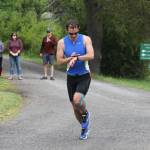 Staff photo. Runner checks watch as he heads off on the last leg of the race.