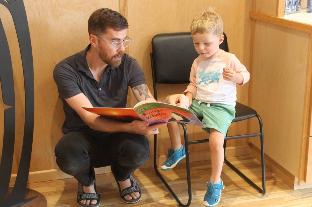 Staff photo/Heather Spaulding. A visitor and his son look at a childrens book.