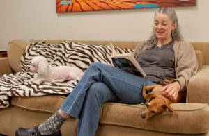 Contributed image/APS-FH                                Shelter volunteer Elizabeth Farr cuddles with dogs while reading in the new enrichment room.