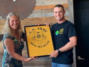 Executive Director Stephanie Buffum presented with 569th plaque by Divemaster Thomas Kneipp. Staff photo/Heather Spaulding.