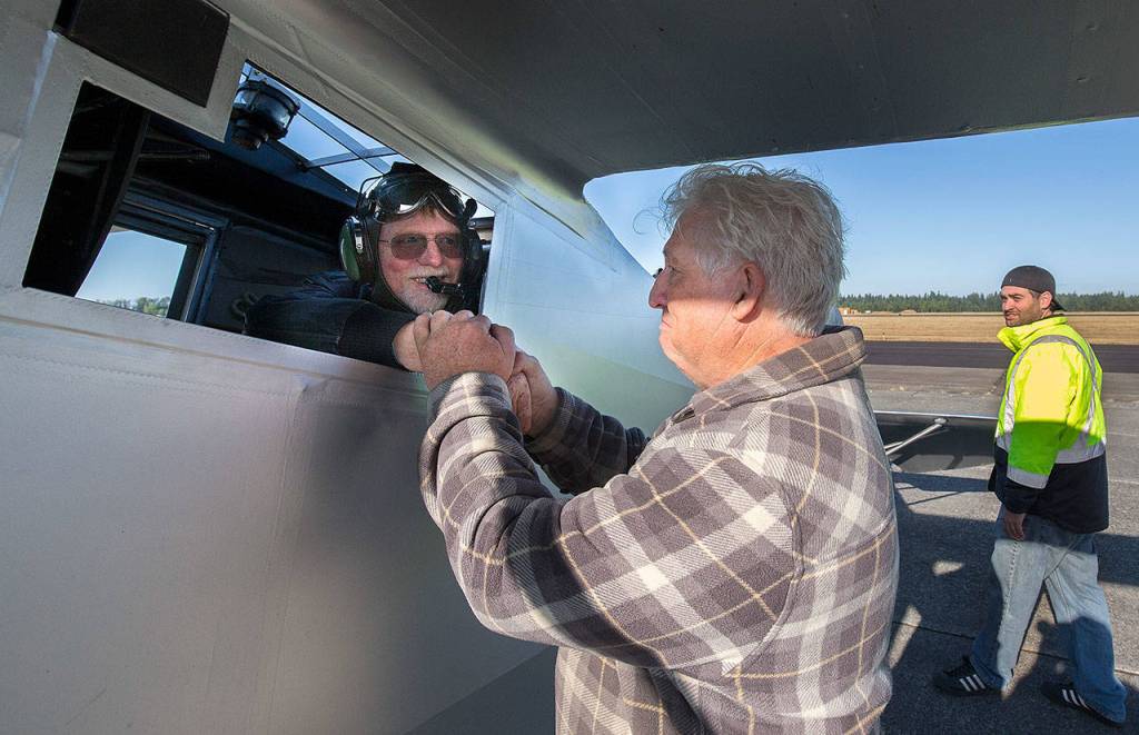 John Norman congratulates pilot Ron Fowlers hand after he successfully flew Normans replica of the Spirit of St. Louis on July 28 in Arlington. (Andy Bronson / The Herald)