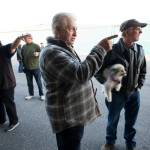 John Norman (center) explains which way pilot Ron Fowler, holding his dog, will take Normans replica of the Spirit of St. Louis out for its first flight at Arlington Municipal Airport on July 28. Heather Norman (left) explains the same to a friend. (Andy Bronson / The Herald)