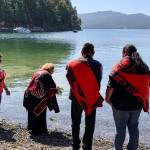 Lummi ceremonialist Tyson Scarborough with Lummi elder Raynell Morris placing cedar boughs in water as part of naming ceremony. Also pictured: witnesses Kevin Paul (Swinomish Tribe); Rueben George (Tsleil-Waututh Nation); Chief Leah George-Wilson (Tsleil-Waututh Nation). <em>(Photo: Lummi Nation Business Council)</em>