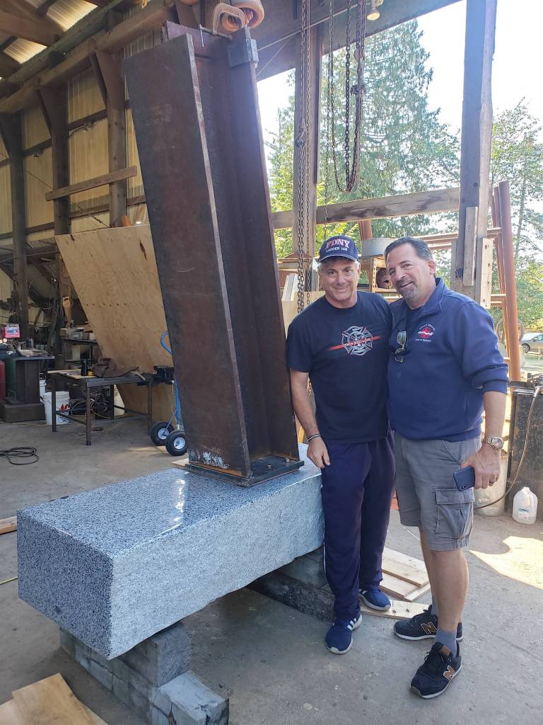 Ron and Alan Stameison share a moment next to the six foot beam and granite slab. The steel beam from the fallen towers has found its forever home at the Eastsound Fire Station on Orcas Island