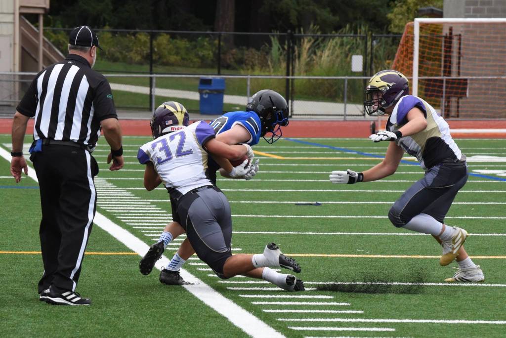 Wolverine Kaden Ritchie (32) drives the Viking ball carrier out of bounds. <em>(John Simpson/Contributed photo)</em>