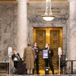 Staff members perform health checks at the entrance to the House Chambers Monday at the Capitol in Olympia. Washington states Legislature will open under a large security presence because of concerns about efforts by armed groups who might try to disrupt the proceedings or occupy the Capitol, which is closed to the public due to the ongoing pandemic. (AP Photo/Ted S. Warren)