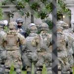 A Washington State Patrol trooper talks with members of the Washington National Guard inside a fence surrounding the Capitol in anticipation of protests Monday in Olympia. (AP Photo/Ted S. Warren)