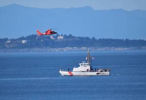 Kelley Balcomb-Bartok / Staff photo
US Coast Guard Cutter Swordfish stands by the scene of the vessel sinking as a Coast Guard helicopter flies overhead.