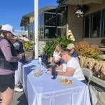 Contributed photo
Players Sue Blaker and Libbey Nixon check out the Wine Raffle and Golf team member Morgan Douglass oversees the donations.