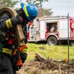 A firefighter recruit pulling deploying hose at live fire training in February.